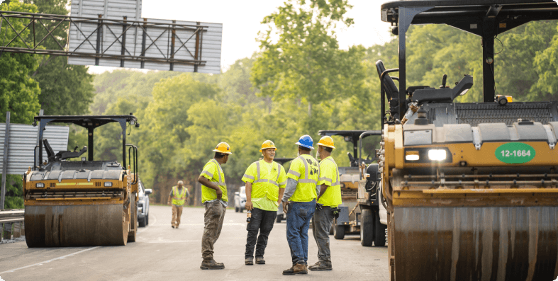 Paving crew standing on a roadway with their rollers