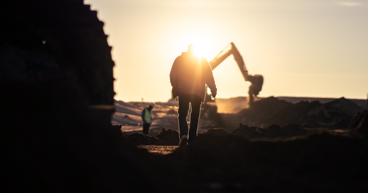 Construction worker walking toward excavator