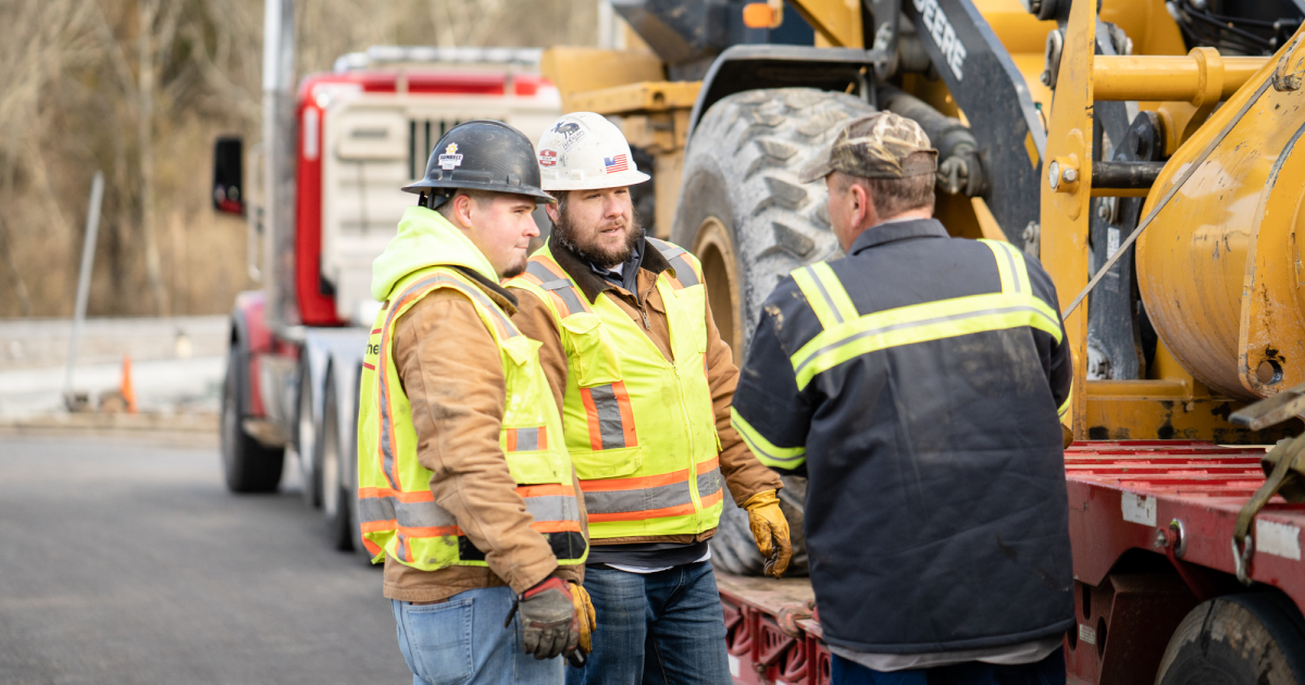 Operators standing beside a machine on a trailer