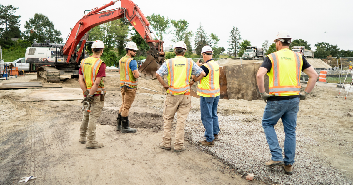 Crew members strategizing near an excavator