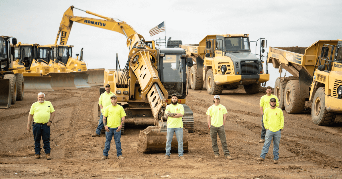 Construction crew standing in front of heavy equipment