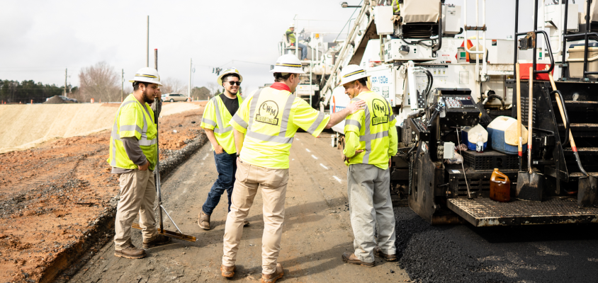 four people with personal protective equipment on a road